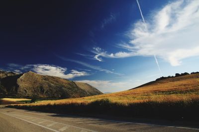 Scenic view of road amidst field against sky