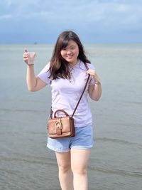 Portrait of young woman standing against sea