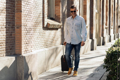 Full length of man walking on footpath near building