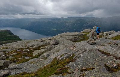 People on rock by mountains against sky