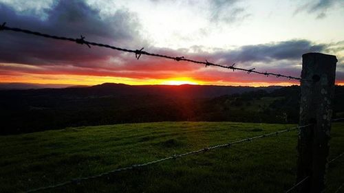 Fence on field at sunset