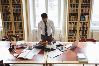 High angle view of professional researching while standing at table in law library