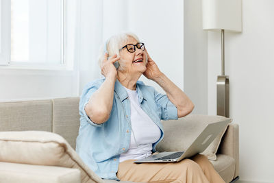 Young woman using laptop while sitting on sofa at home