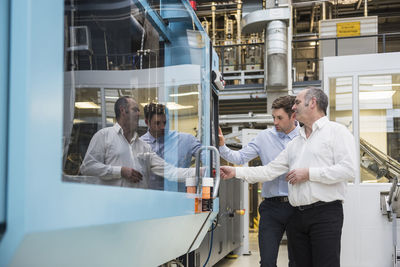 Two men looking at machine in factory shop floor