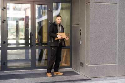 Happy man ringing intercom with camera in entryway.