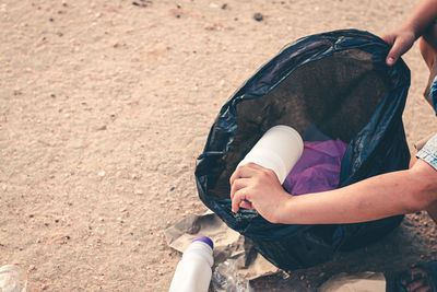 Cropped hand of person collecting garbage on sand