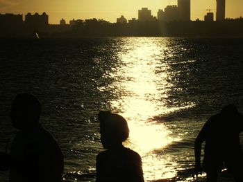 Silhouette man standing by sea against sky during sunset