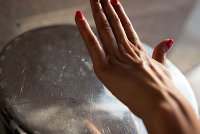 Cropped hand of woman over silver container