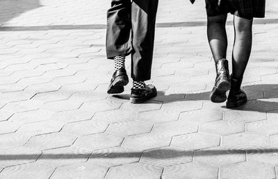 Low section of friends walking on footpath