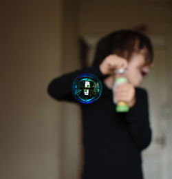 Digital composite image of woman holding crystal ball against wall