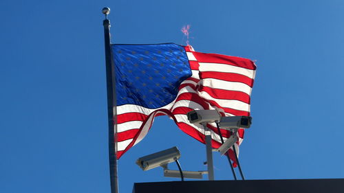 Low angle view of flag waving against clear blue sky