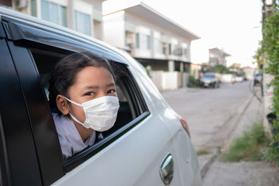 A child wearing a sanitary mask popped his head out of the car window.