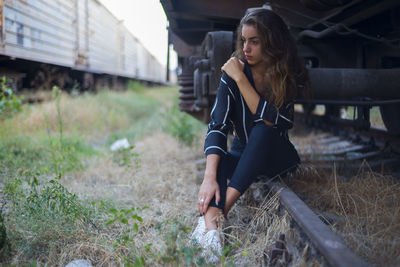 Full length of thoughtful woman sitting at shunting yard