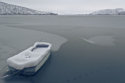 Snow covered boat moored at frozen lake