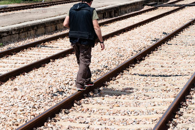 Low section of man walking on railroad track