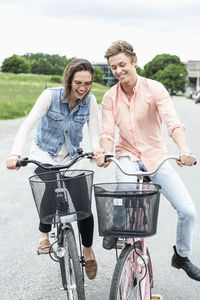 Young friends enjoying bicycle ride on country road