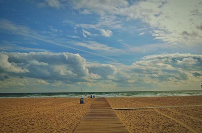 Scenic view of beach by sea against cloudy sky