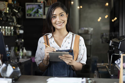 Portrait of smiling young barista working in cafe