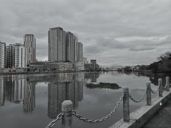Bridge over river by buildings against sky