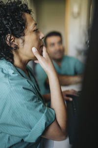 Female doctor with hand on chin using computer in hospital