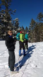 Full length of friends skiing on snowy field against clear blue sky