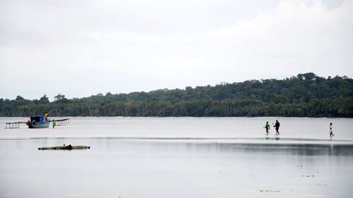 People on lake against sky