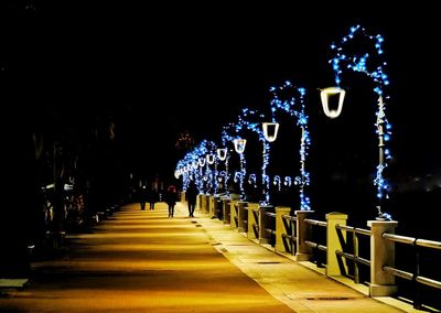 People walking on illuminated footpath at night