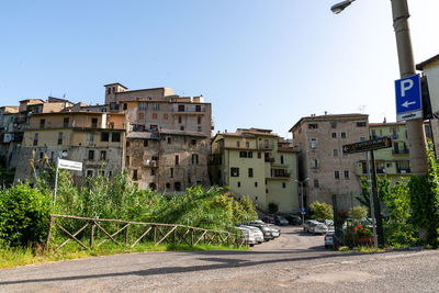 Road by buildings against clear sky