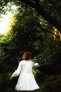 Rear view of woman standing against trees