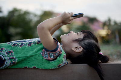 Girl using mobile phone while lying outdoors