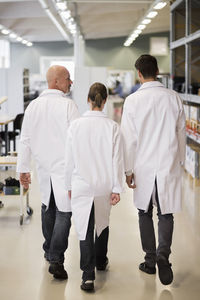 Rear view of engineers walking in factory