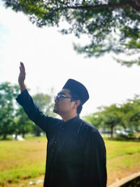 Side view of man waving while standing on land