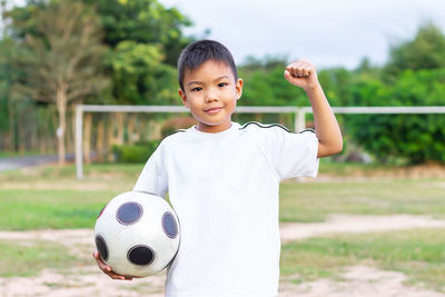 Portrait of boy with ball on field