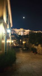 Illuminated street amidst buildings in city at night