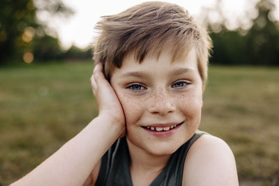 Portrait of happy boy with freckles leaning on elbow