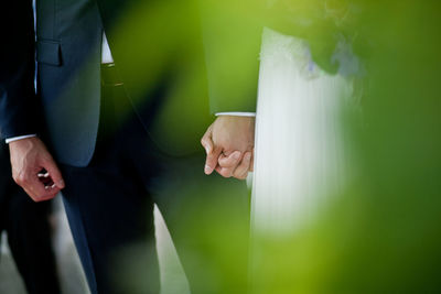 Midsection of bride and bridegroom holding hands during wedding