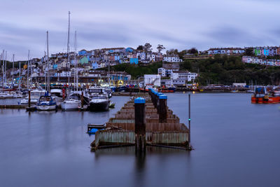 Boats in marina at harbor against sky in city