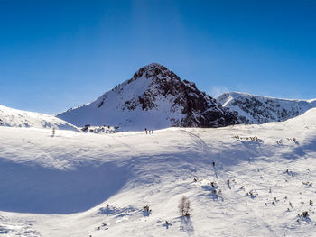 Scenic view of snowcapped mountains against clear blue sky