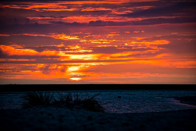 Scenic view of sea against dramatic sky during sunset