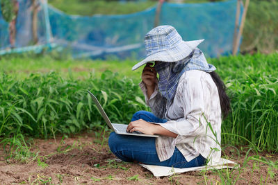 Side view of man using mobile phone in field