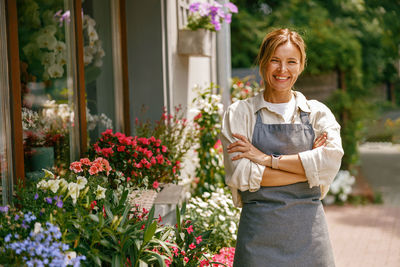 Portrait of smiling young woman standing in greenhouse