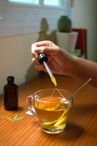 Midsection of person pouring tea in glass on table