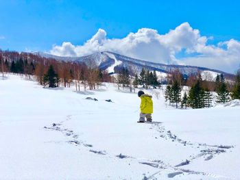 Rear view of person on snow covered mountain against sky