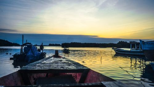 Boats moored in sea against sky during sunset