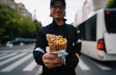 Man holding ice cream standing on street