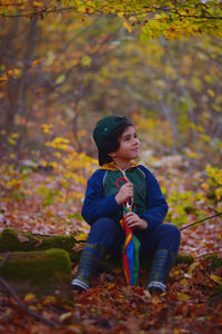 Young woman standing by tree trunk