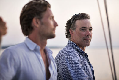 Men looking away while standing at yacht