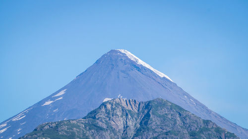 Low angle view of snowcapped mountain against clear blue sky