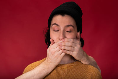 Close-up portrait of young woman against red background