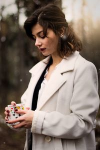 Young woman looking away while standing outdoors